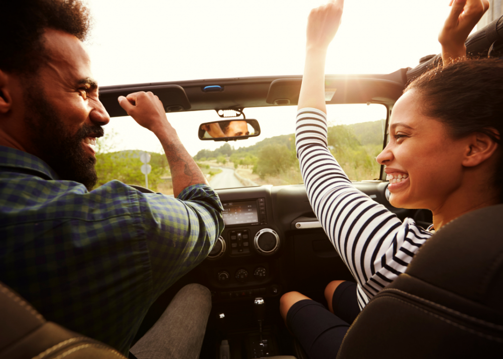 Photo of two people in a convertible driving on a road